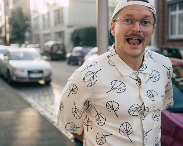 Foto von Jannis Johannmeier draußen mit gemustertem Hemd, lächelnd 