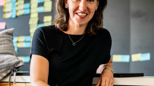 Claudia Feiner sitzt vor einer Tafel mit Postits; Text:'Moderne Arbeitswelten'