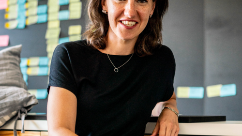 Claudia Feiner sitzt vor einer Tafel mit Postits; Text:'Moderne Arbeitswelten'