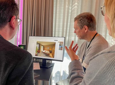 Teilnehmer diskutieren an einem Monitor über KI-generierte Homestaging-Bilder.