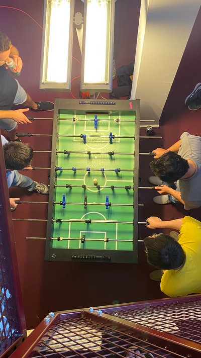 Draufsicht von oben auf eine Tischfußballrunde mit mehreren Spielern.