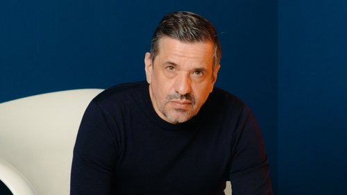 Raphael Gielgen, sitzend in einem weißen Stuhl vor einem dunkelblauen Hintergrund.