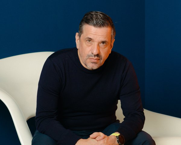 Raphael Gielgen, sitzend in einem weißen Stuhl vor einem dunkelblauen Hintergrund.