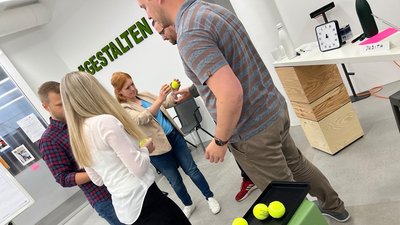 Ball Point Game - 5 Personen stehen im Kreis und reichen sich Tennisbälle