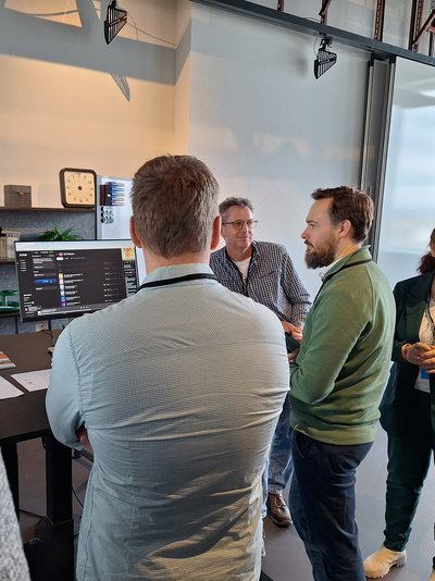 Drei Teilnehmer der KI-Expedition tauschen sich an einem Bildschirm aus.