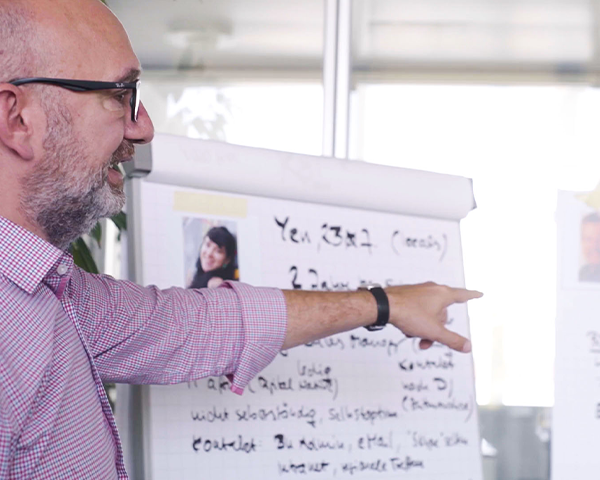 Oliver Kemman weist auf Whiteboard mit Persona Beispiel